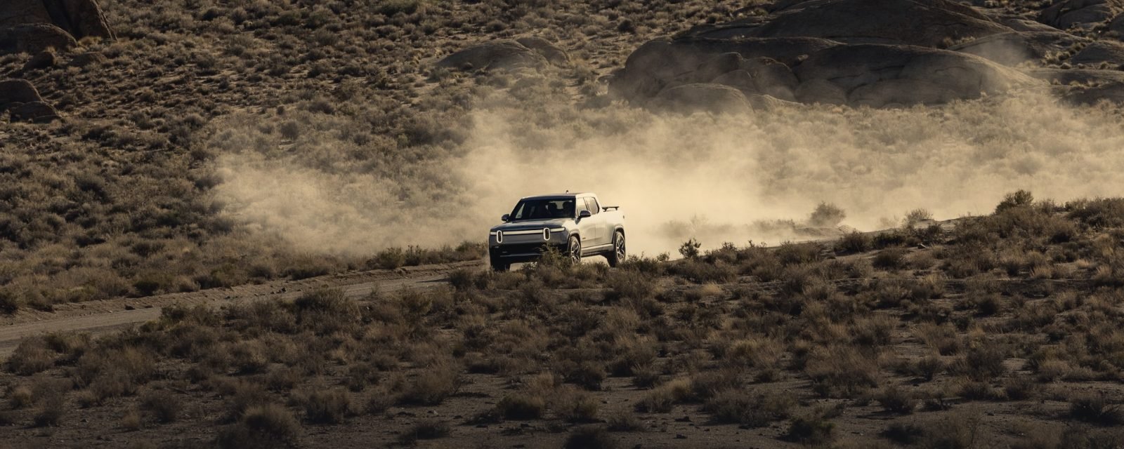 A pickup truck raising dust on a desert road