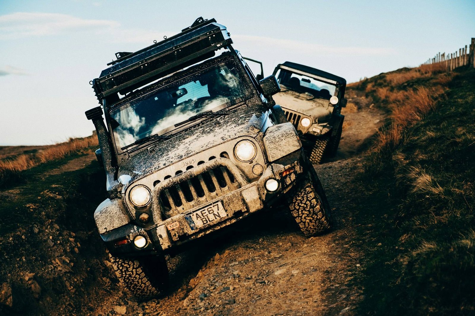 Two Jeep Wranglers covered in mud driving off-road