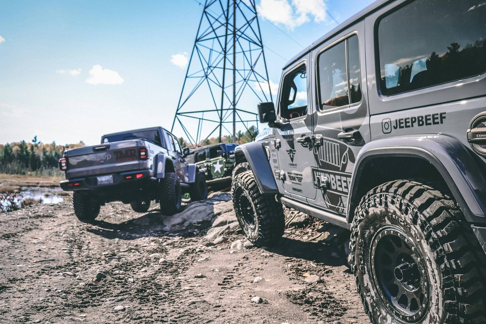 Two Jeeps parked in deep mud near a power line cut