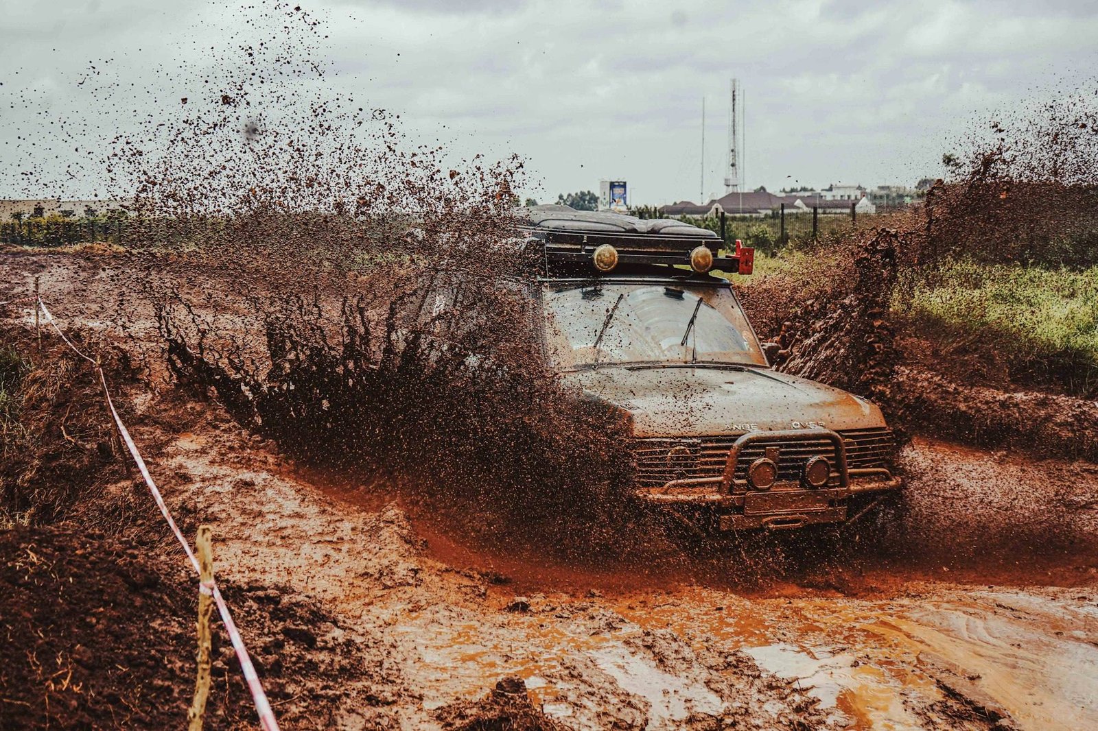 An old 4x4 with a bull bar churning through deep red mud