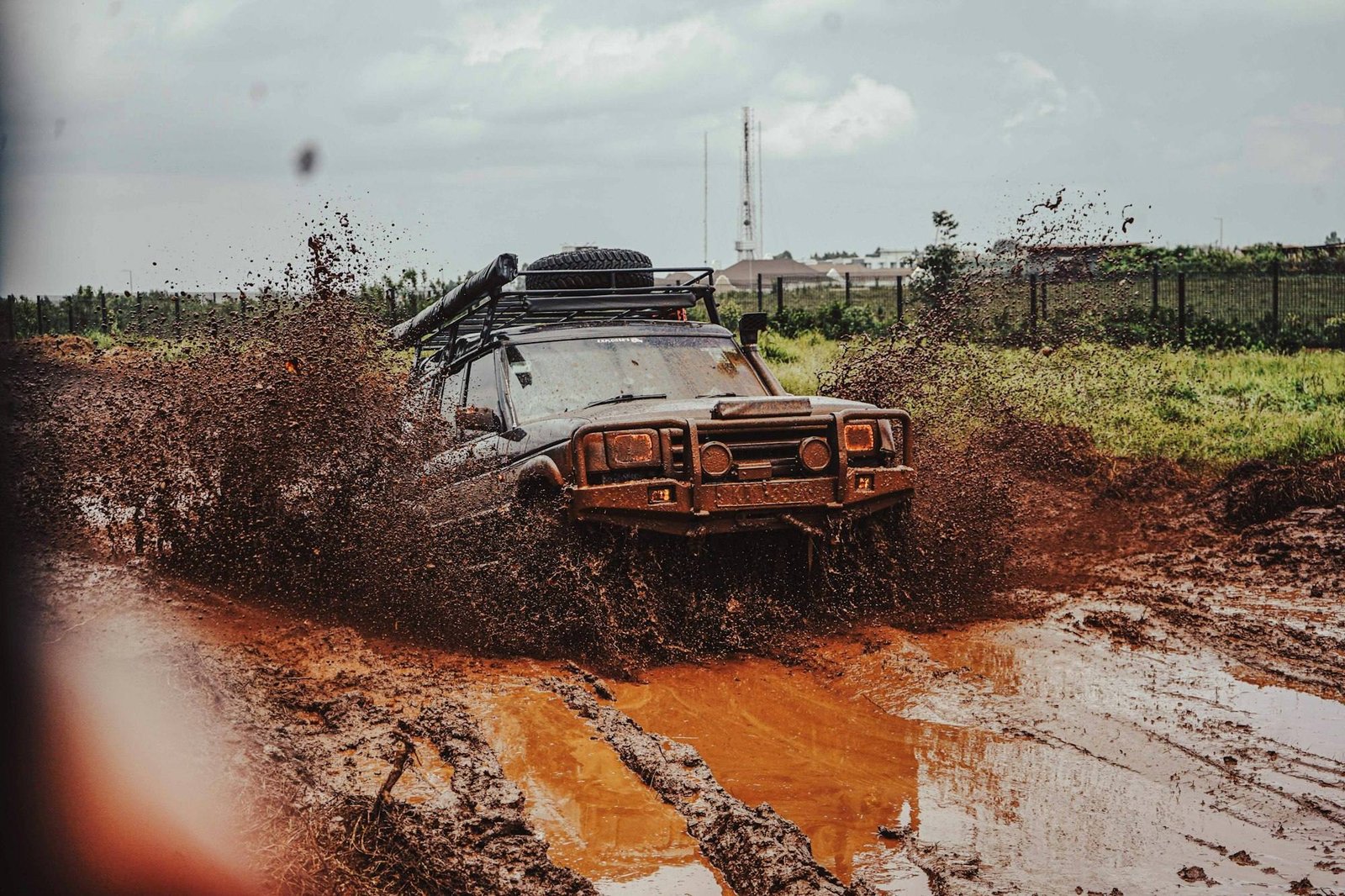 An old 4x4 with a snorkel and bull bar crossing a muddy track